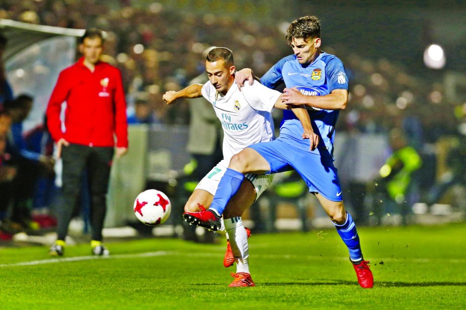 Real Madrid's Lucas Vazquez, left, tussles for the ball with Fuenlabrada's Fran Garcia during a Spanish Copa del Rey round of 32 first leg soccer match between Fuenlabrada and Real Madrid at the Fernando Torres stadium in Fuenlabrada, outside Madrid on