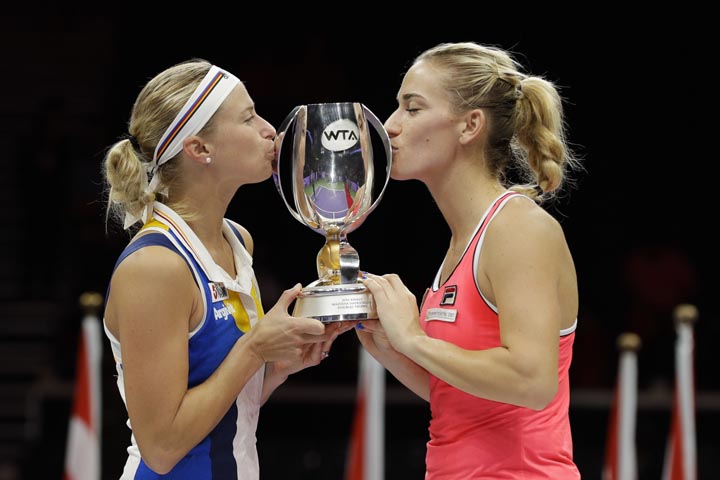 Andrea Hlavackova of the Czech Republic, left, and Timea Babos of Hungary kiss the winners' trophy after beating Kiki Bertens of the Netherlands and Johanna Larsson of Sweden during their doubles final match at the WTA tennis tournament in Singapore on S