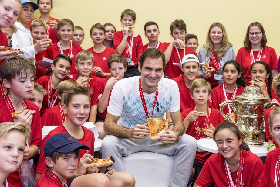 Switzerland's Roger Federer eats pizza with ball boys and girls after winning the final match against Argentina's Juan Martin del Potro at the Swiss Indoors tennis tournament at the St. Jakobshalle in Basel, Switzerland on Sunday.