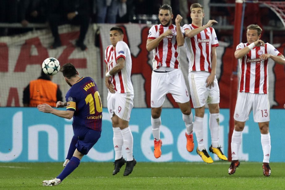 Olympiakos players jump as Barcelona's Lionel Messi takes a free kick during the Champions League group D soccer match between Olympiakos and Barcelona at Georgios Karaiskakis stadium at Piraeus port, near Athens on Tuesday.