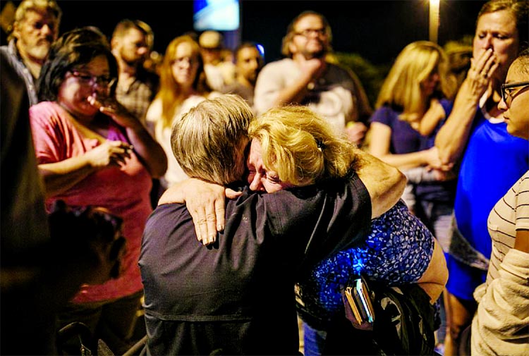 Texas Gov. Greg Abbott consoles Ann Montgomery, a Sunday school teacher at First Baptist Church, during a candlelight vigil.