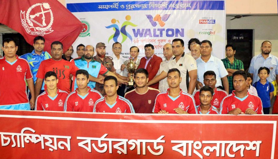 Members of Border Guard Bangladesh, the champions of the Men's Group of the Walton 6th Services (Men's & Women's) Wrestling Competition with the guests and officials pose for a photo session at the Shaheed (Captain) M Mansur Ali National Handball Stadi