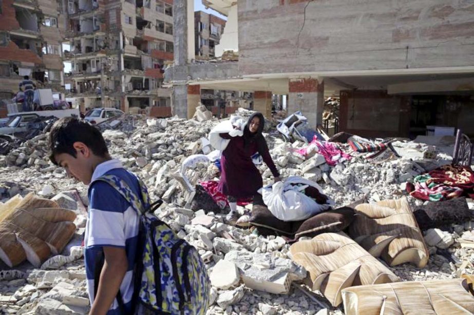 People clean away debris in Sarpol-e-Zahab, Iran on Wednesday after a powerful earthquake along the Iran-Iraq border.