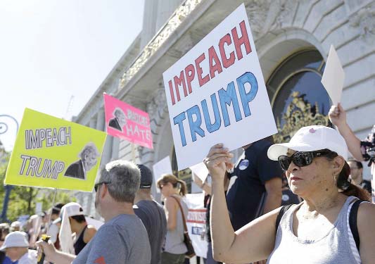 People hold up signs at a rally calling for the impeachment of President Donald Trump in San Francisco.