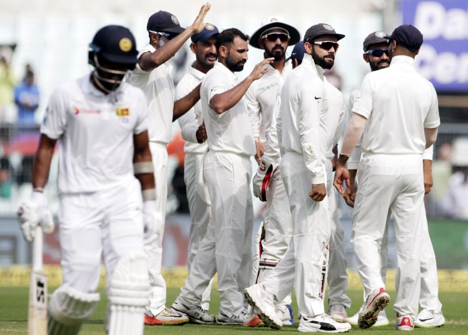 India's Mohammed Shami (center without cap) celebrates with teammates the dismissal of Sri Lanka's Dinesh Chandimal (left) during the fourth day of their first Test cricket match in Kolkata, India on Sunday.