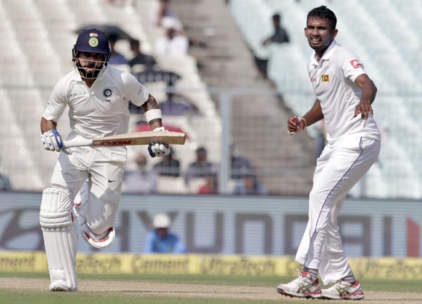 Sri Lanka's Dasun Shanaka (right) watches India's captain Virat Kohli run between the wickets during the fifth day of their first test cricket match in Kolkata, India on Monday.
