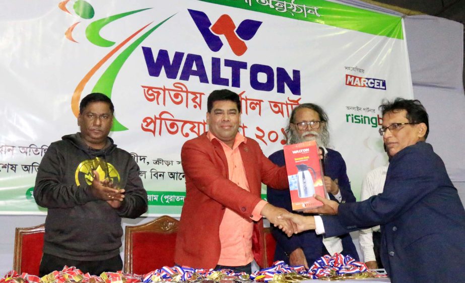 Operative Director (Head of Sports & Welfare Department) of Walton Group FM Iqbal Bin Anwar Dawn (second from left) handing over a home appliance of Walton to an official of Bangladesh Martial Art Confederation at the Gymnasium of National Sports Council