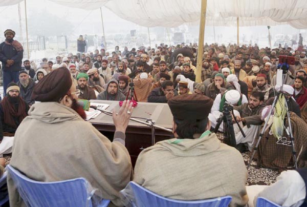 Supporters of religious groups listen to their leader at a rally to express solidarity with protesters, in Lahore on Sunday