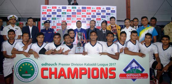 Members of Bangladesh Ansar and VDP team pose for photo with guests and trophy of Dhaka Metropolis First Division Volleyball League at Dhaka Volleyball Stadium on Monday.