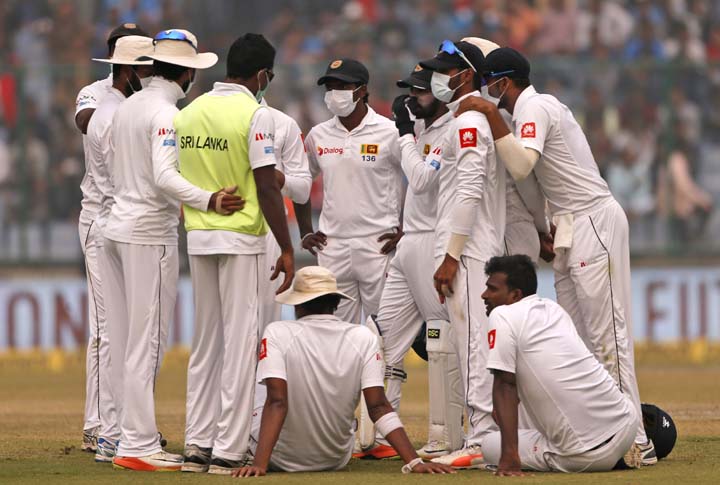 Sri Lanka's players wearing anti-pollution masks speak to each other as the game was briefly stopped during the second day of their third Test cricket match in New Delhi, India on Sunday.
