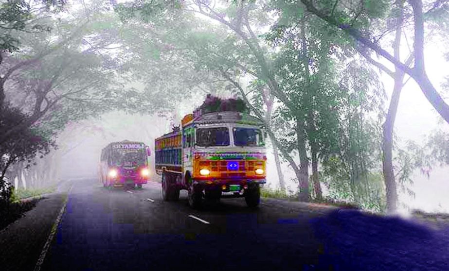 Heavy vehicles plying on Dhaka-Chittagong Highway with lighting in day time due to heavy dense fog at the beginning of the winter. This photo was taken on Monday.