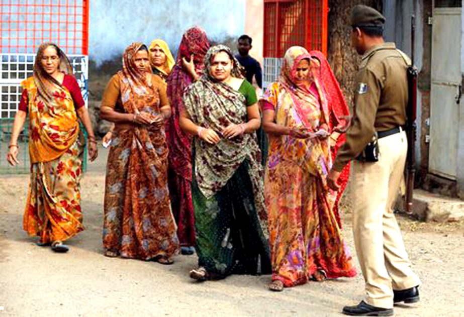 A policeman checks identity papers of women as they arrive to cast their votes at a polling station during the first phase of Gujarat state assembly election in Panshina village of Surendranagar district on Saturday.