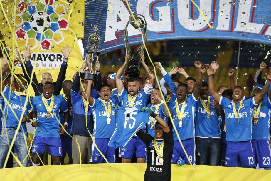 Andres Cadavid of Millonarios holds his team's trophy over his head (center) after winning the final Colombian soccer league championship title, on aggregate 3-2 against Independiente Santa Fe, in Bogota, Colombia on Sunday.