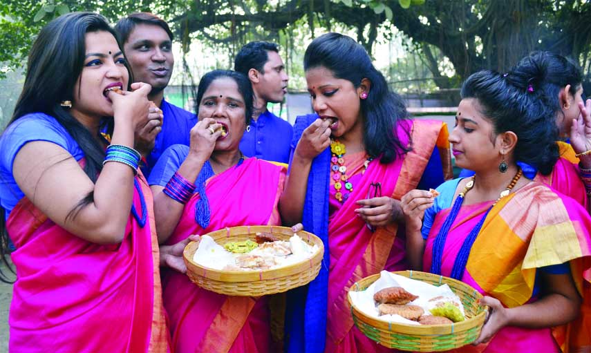 Visitors seen to eat winter cakes at a stall of 'Poush Mela' organised by 'Poush Mela Udjapon Parishad' at Bangla Academy in the city on Friday.