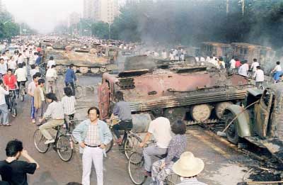 Beijing residents gather around the smoking remains of over 20 armoured personnel carriers-burnt by demonstrators during clashes with soldiers near Tiananmen Square.