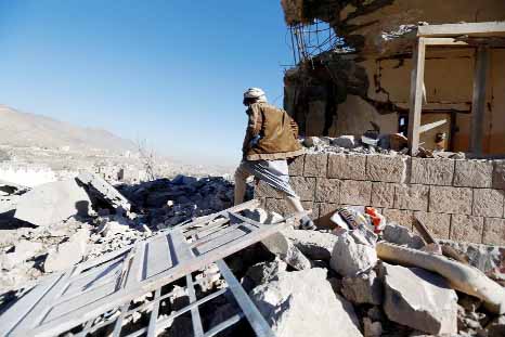 A man walks past a destroyed house at the site of air strikes in Sanaa, Yemen.