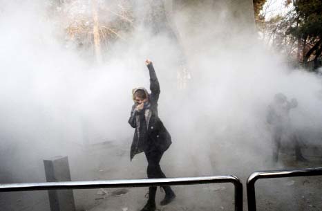 A woman raises her fist amid tear gas at the University of Tehran during a protest on Saturday.