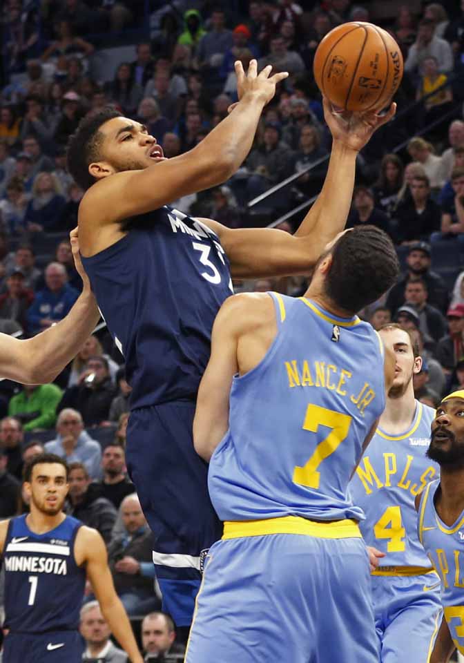 Minnesota Timberwolves' Karl-Anthony Towns (left) attempts a layup as he is fouled by Los Angeles Lakers' Larry Nance Jr. defends in the first half of an NBA basketball game in Minneapolis on Monday.