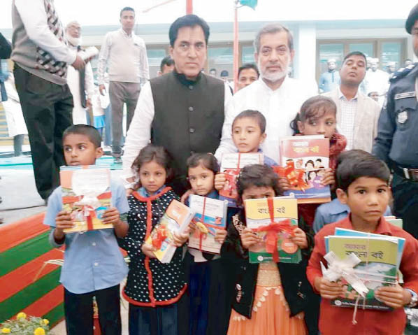 Chairman of the Parliamentary Standing Committee on Ministry of Railway ABM Fazle Karim Chowdhury MP distributing text books among primary school students at a simple ceremony at Raozan Upazila Complex ground on Monday morning as Chief Guest.