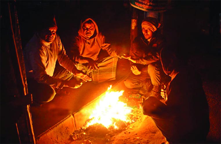 Cold-stricken poor people warm themselves sitting around a fire. The snap was taken from the city's Karwan Bazar on Thursday.