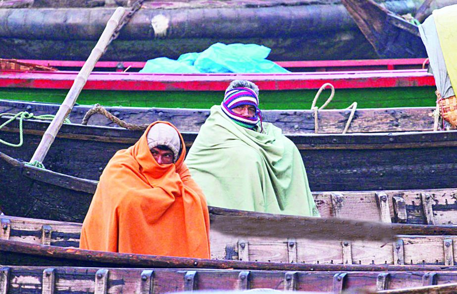 Two boatmen in Buriganga river caught in cold as mercury fell across the capital and elsewhere. This photo was taken from Sadarghat area on Saturday.