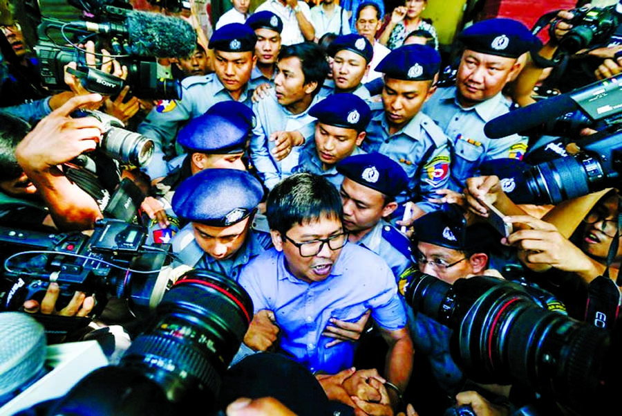 The Reuters journalists U Wa Lone, center front, and U Kyaw Soe Oo, center back, were escorted by the police in Yangon after being charged with obtaining state secrets on Wednesday.