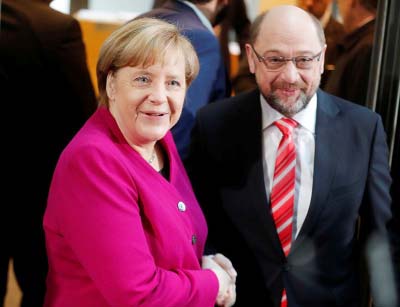 Leader of the Christian Democratic Union (CDU) and the acting German Chancellor Angela Merkel and Social Democratic Party (SPD) leader Martin Schulz shakes hands before exploratory talks about forming a new coalition government at the SPD headquarters in