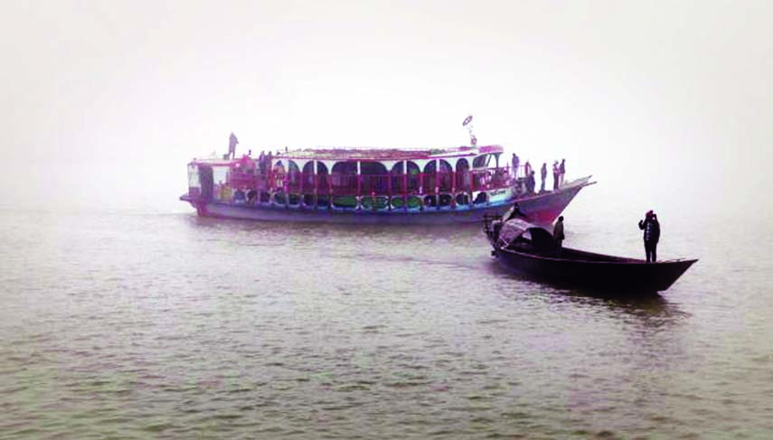 Launches and boats are seen to ply in dense fog taking risk of accident any time. The snap was taken from the Padma river in Maowa on Saturday.