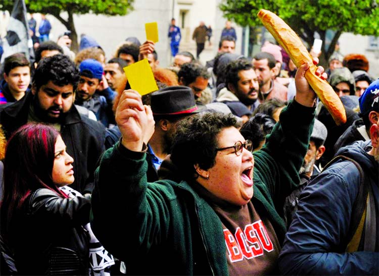 A Tunisian woman holds up a yellow card and a loaf of bread during a protest against price hikes and austerity measures in the capital Tunis.