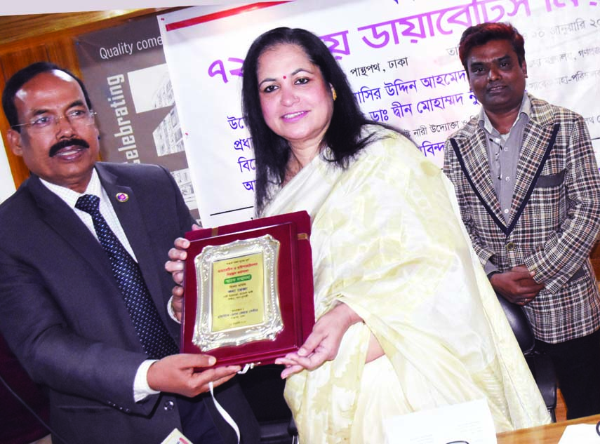 Managing Director of Holistic Health Care Center Prof Dr Govinda Chandra Das handing over a crest to the CEO of Pansupari and women entrepreneur Kona Reza at a workshop on diabetes in the SEL Center auditorium in the city's Panthapath on Thursday.