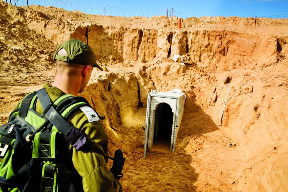 An Israeli soldier stands next to an entrance to what the Israeli military say is a cross-border attack tunnel dug from Gaza to Israel, on the Israeli side of the Gaza Strip border near Kissufim, Israel.