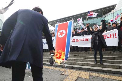 South Korean protestors burn a North Korean flag during an anti-North Korea rally outside Seoul station in Seoul on January 22, 2018 as a North Korean delegation arrives at the station.