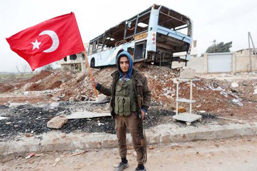 A Turkey-backed Free Syrian Army fighter holds a makeshift Turkish flag as he patrols on a road near Azaz, Syria.