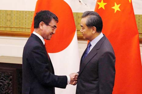 Japan's Foreign Minister Taro Kono shakes hands with his Chinese counterpart Wang Yi in Beijing, as ties between Asia's two largest economies show signs of warming