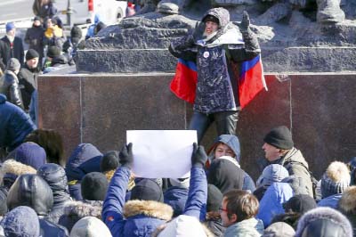 A demonstrator with a Russian national flag wrapped in his shoulders shouts slogans during a rally in Vladivostok, Russia on Sunday.