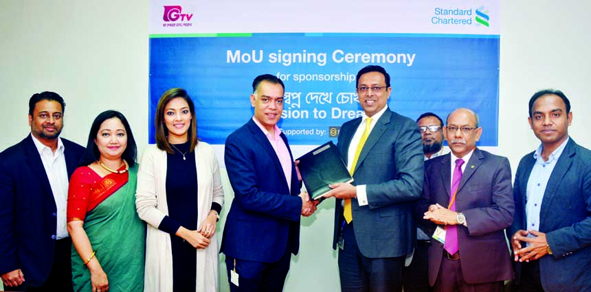 Aman Ashraf Faiz, Managing Director of Gazi Satellite Television Limited and Naser Ezaz Bijoy, CEO of Standard Chartered Bank Bangladesh, exchanging an MoU signing documents on a project titled "Shopno Dekhe Chokh" With technical support from Sightsaver