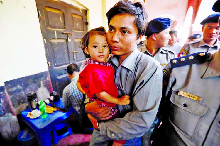 Detained Reuters journalist Kyaw Soe Oo carries his daughter Moe Thin Wai Zin while being escorted by police during a break at a court hearing in Yangon, Myanmar February 1, 2018. Internet photo