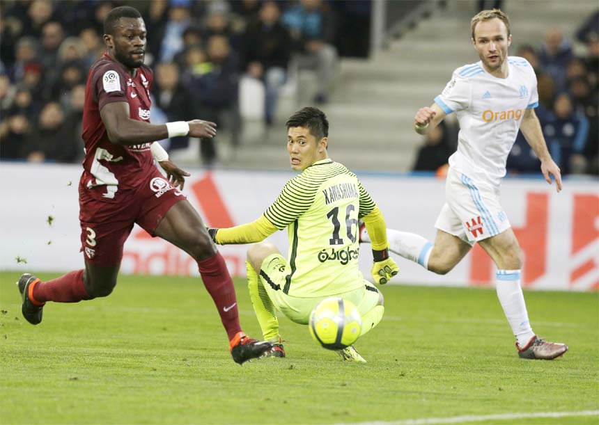 Marseille's Valere Germain (right) scores despite Metz's goalkepper Eiji Kawashima (center) and Metz's Fallou Diagne, during the League One soccer match between Marseille and Metz, at the Velodrome Stadium in Marseille, southern France on Friday.