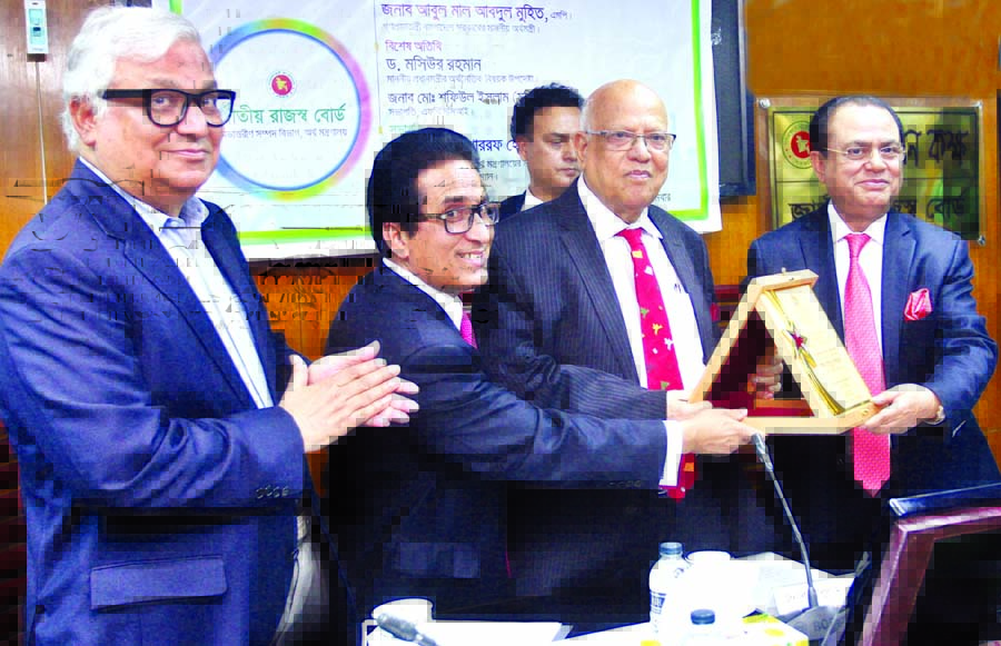 Finance Minister Abul Maal Abdul Muhith giving citation crest to the former minister Syed Abul Hossain as the highest taxpayer in the conference room of the National Board of Revenue in the city on Monday.