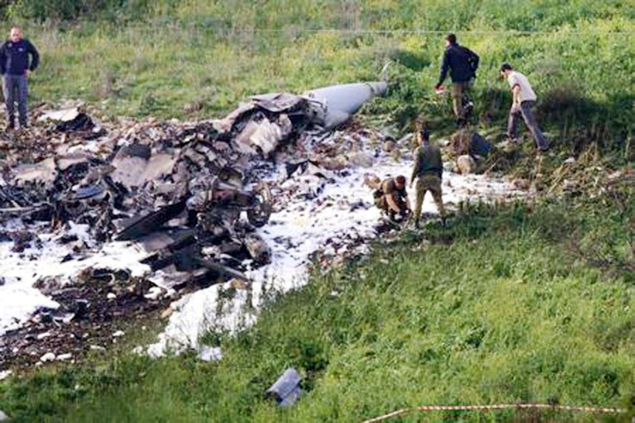Israeli security forces walk next to the remains of an F-16 Israeli war plane near the Israeli village of Harduf, Israel on Saturday.