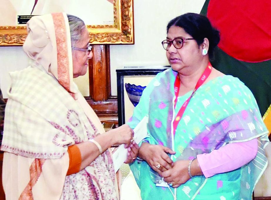 Prime Minister Sheikh Hasina handing over a cheque of financial assistance to cine actress Begum Khaleda Akhter Kalpana at Ganobhaban on Friday for her treatment of eye and diabetes. BSS photo
