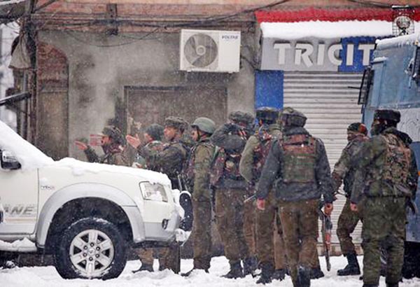 Indian policemen stand near the site of a gunbattle with suspected militants during a snowfall in Srinagar on Monday.