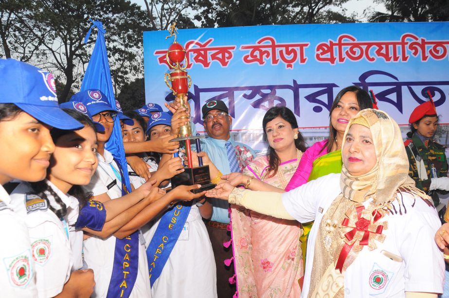 Begum Farzana Hasan, wife of Major General Ataul Hakim Sarwar Hasan, Area Commander of Logistic Area, handing over the trophy to the members of Begum Rokeya House, the champions of the Annual Sports Competition of Shaheed Bir Uttam Lieutenant Anwar Girls