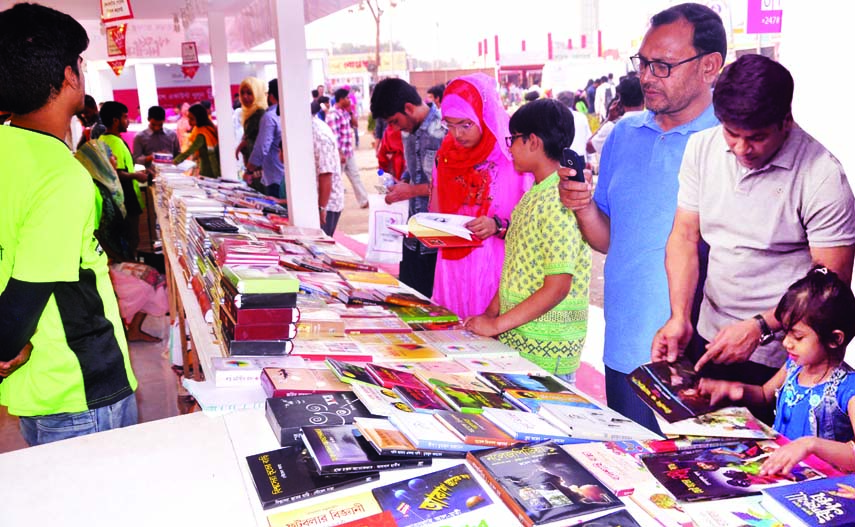 Buyers flip through the books at a stall of Amar Ekushey Book Fair on Bangla Academy premises in the city on Monday.