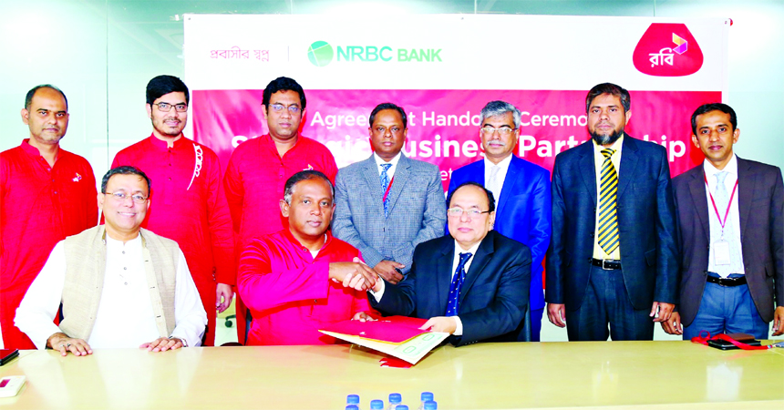 Mahtab Uddin Ahmed, CEO of Robi and Kazi Md. Talha, Managing Director of NRB Commercial Bank Limited, exchanging an agreement signing documents at Robi's Corporate Office in the city on Sunday. Senior officials from both the organizations were also prese