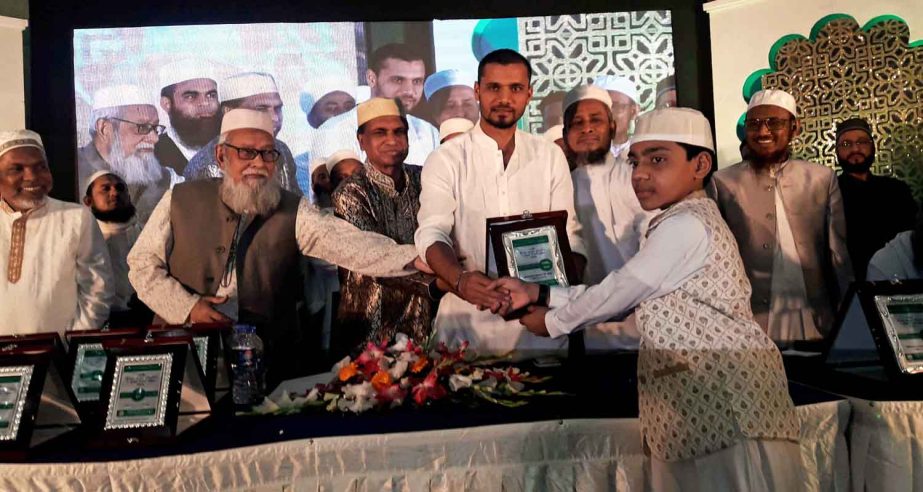 Captain of Bangladesh National Cricket (ODI) team Mashrafe Bin Mortaza handing over a crest of honour to Hafiz Yasin Arafat at the Bashundhara International Convention Centre in the city recently. Yasin Arafat became Hafiz-e-Quran in 86 days. He was a stu