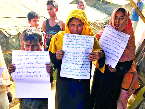 A group of Myanmar refugees, both male and female, stood in line carrying placards with their demands regarding repatriation at Balukhali camp in Teknaf recently. Their 9- point demands includes ensuring their recognition as Mymanmar nationals, involvemen