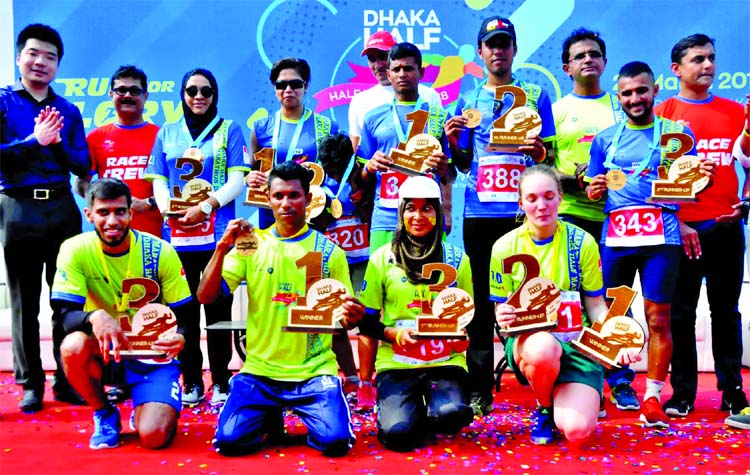 The winners of 'Dhaka Half Marathon' and 'Dhaka Mini Marathon' with the organizers of the meet pose for photograph at Hatirjheel in the city on Friday.
