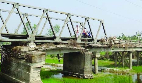 NILPHAMARI: People with heavy and light vehicles crossing hundred years old risky bridge at Gomnati Union in Domar Upazila . The bridge needs immediate repair.