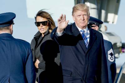 President Donald Trump, accompanied by first lady Melania Trump, waves to members of the media as they arrive at Andrews Air Force Base on Saturday